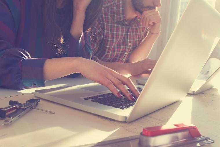 Person typing on a laptop during a meeting. 