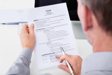 A person holding and reviewing a printed resume document.