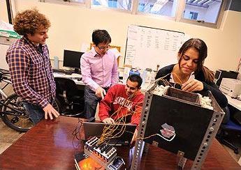 Four people collaborating around a computer in an office setting.
