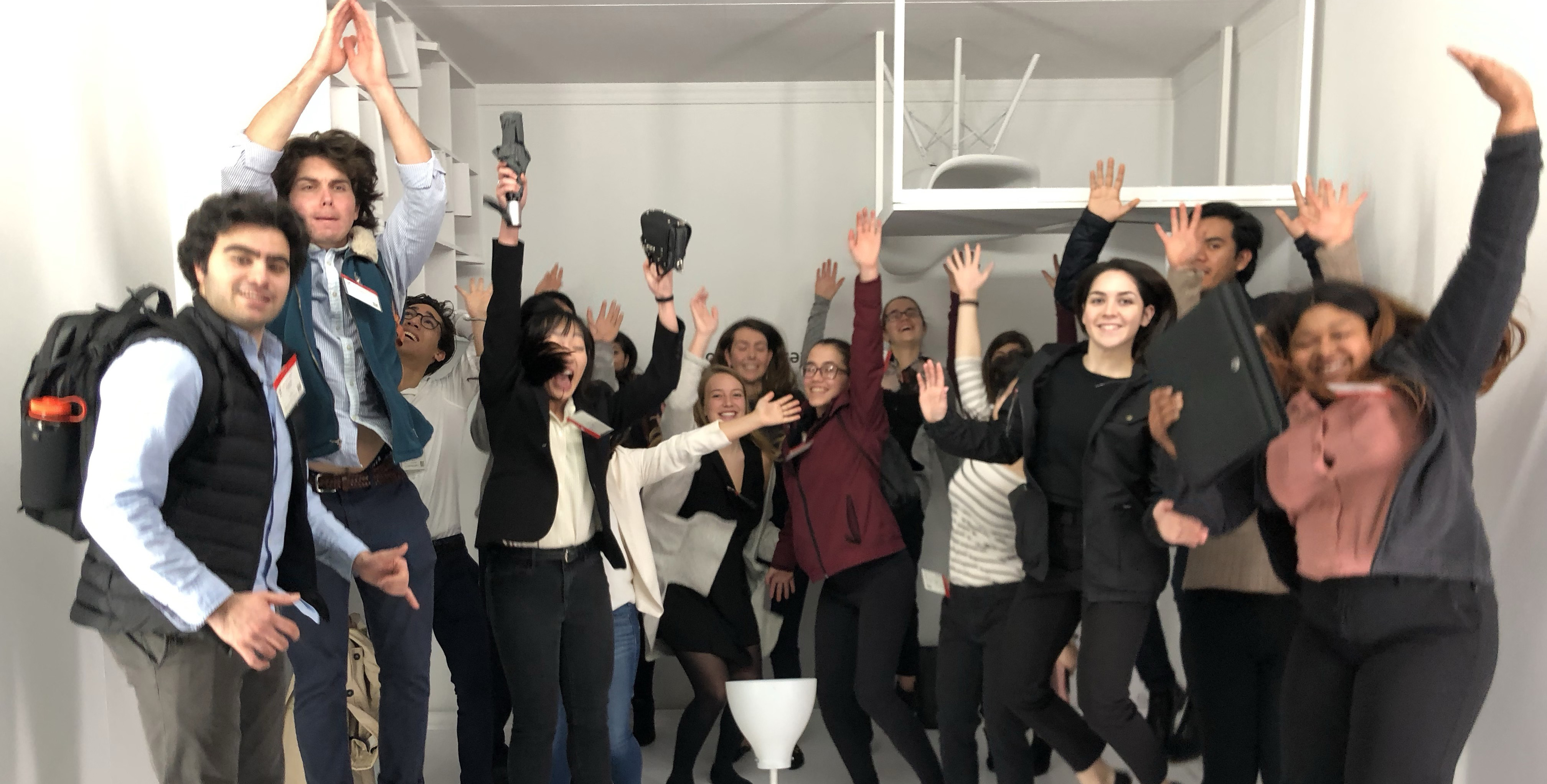 Group of people posing together indoors with cheerful expressions and raised arms.