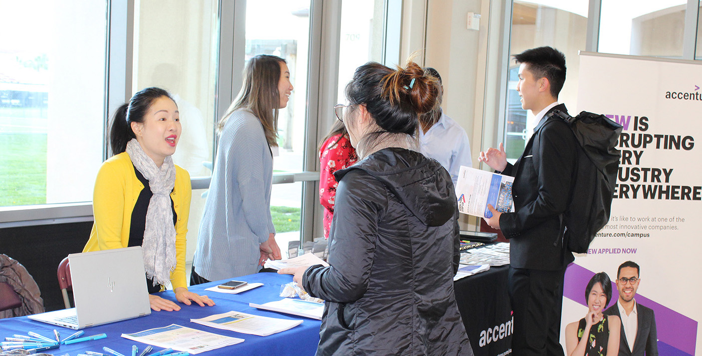 People networking at a Diversity Works event with a blue table in the foreground.