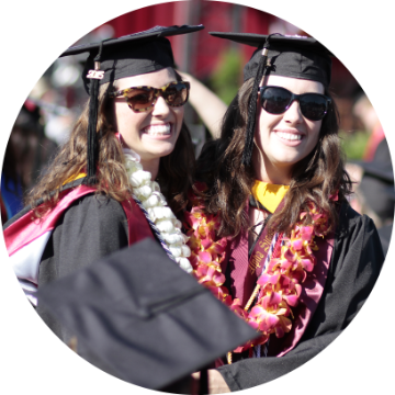 Graduates in caps and gowns smiling at a commencement ceremony.