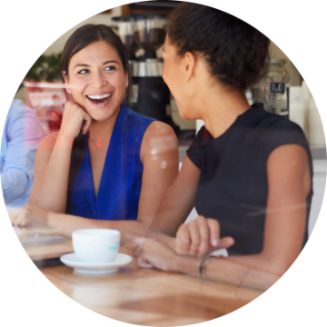 Two women seated at a table, talking and smiling.