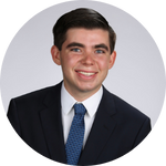 A person in formal attire smiling against a plain background.