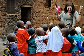 A group of children outdoors with a person holding toys.