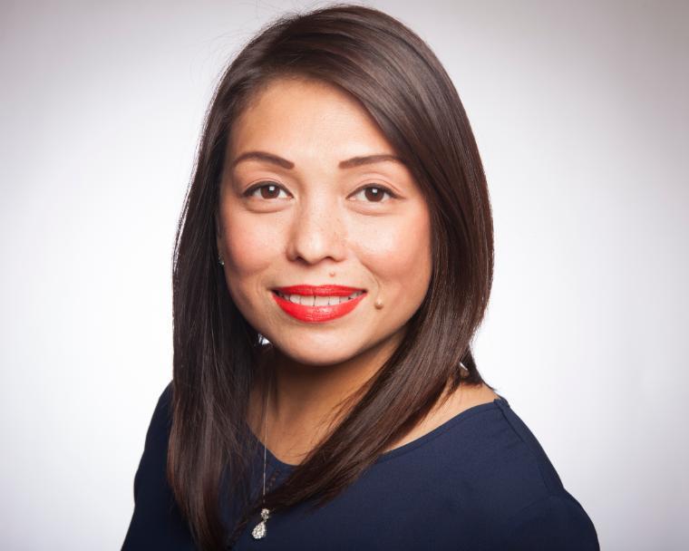 A woman smiling against a plain background.