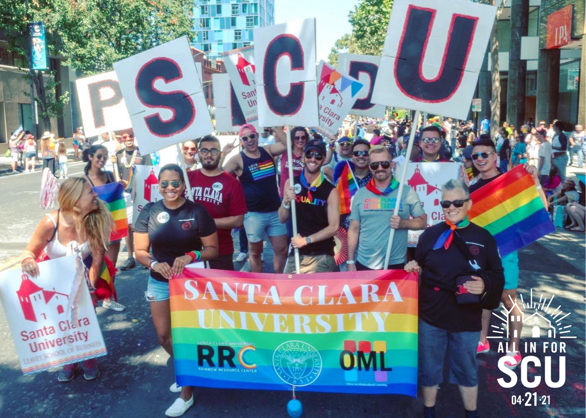 A group of people holding signs and a rainbow banner reading Support the University.