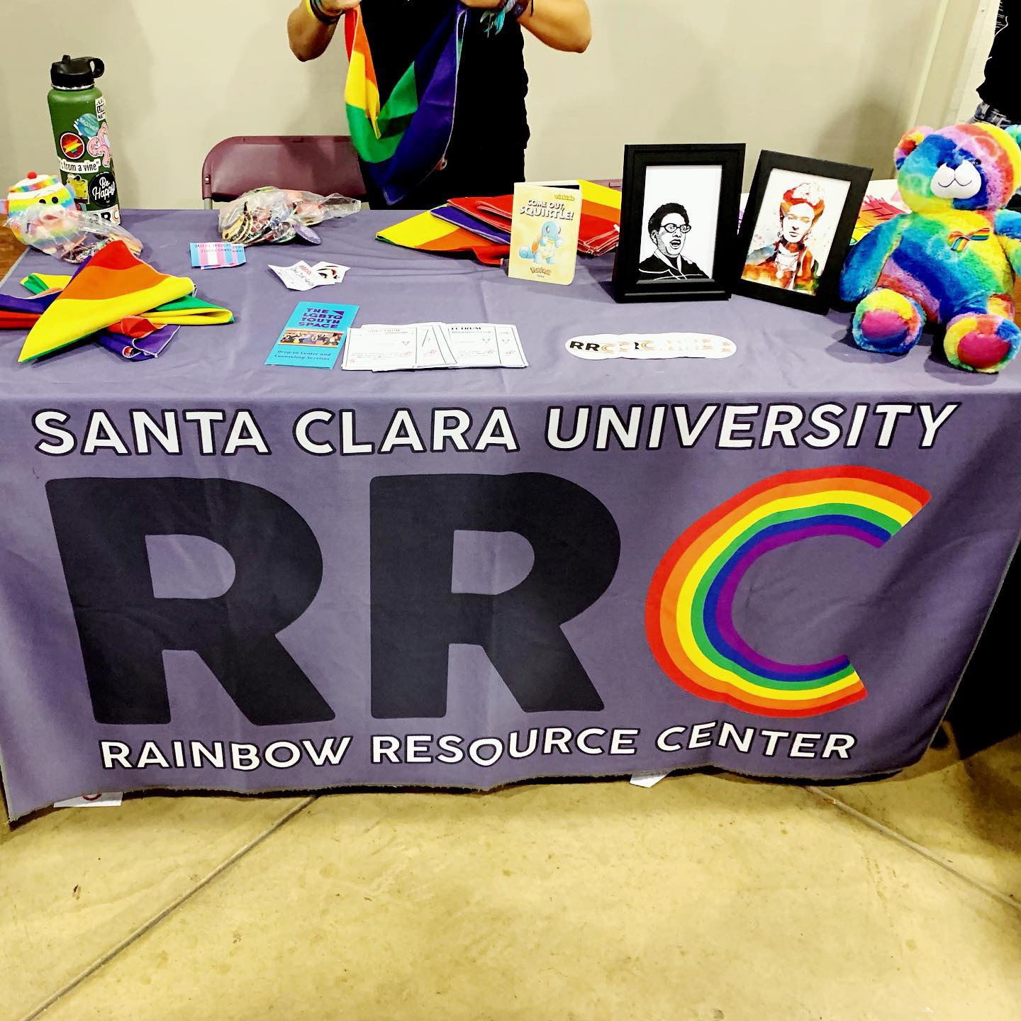 Table with SANTA CLARA UNIVERSITY RAINBOW RESOURCE CENTER banner and various items displayed.