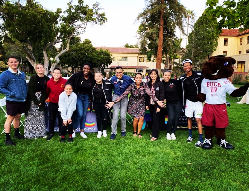A group of people pose outdoors on a grassy area.