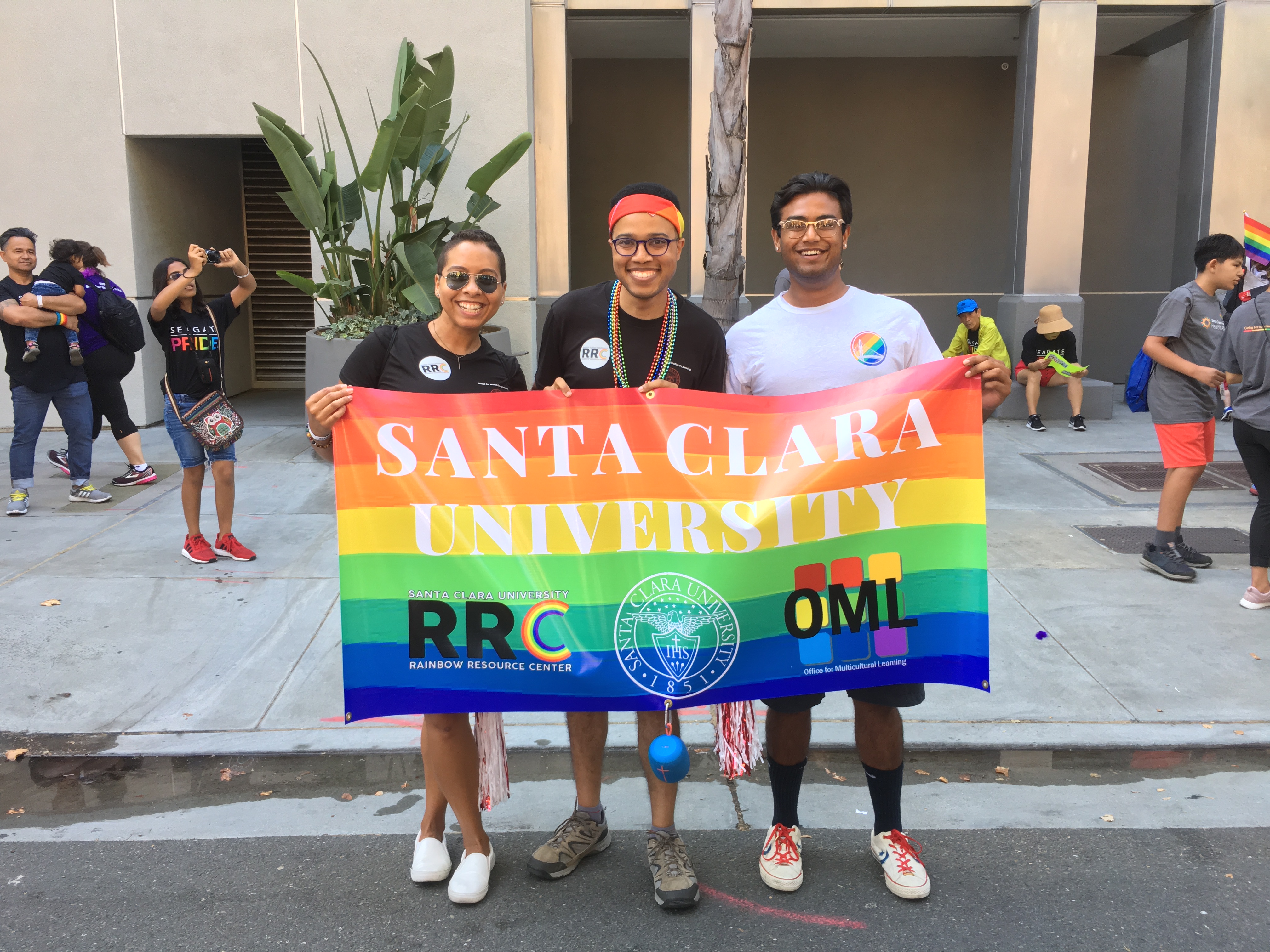 Three people holding Valley International Prep High School rainbow pride flag at a parade.