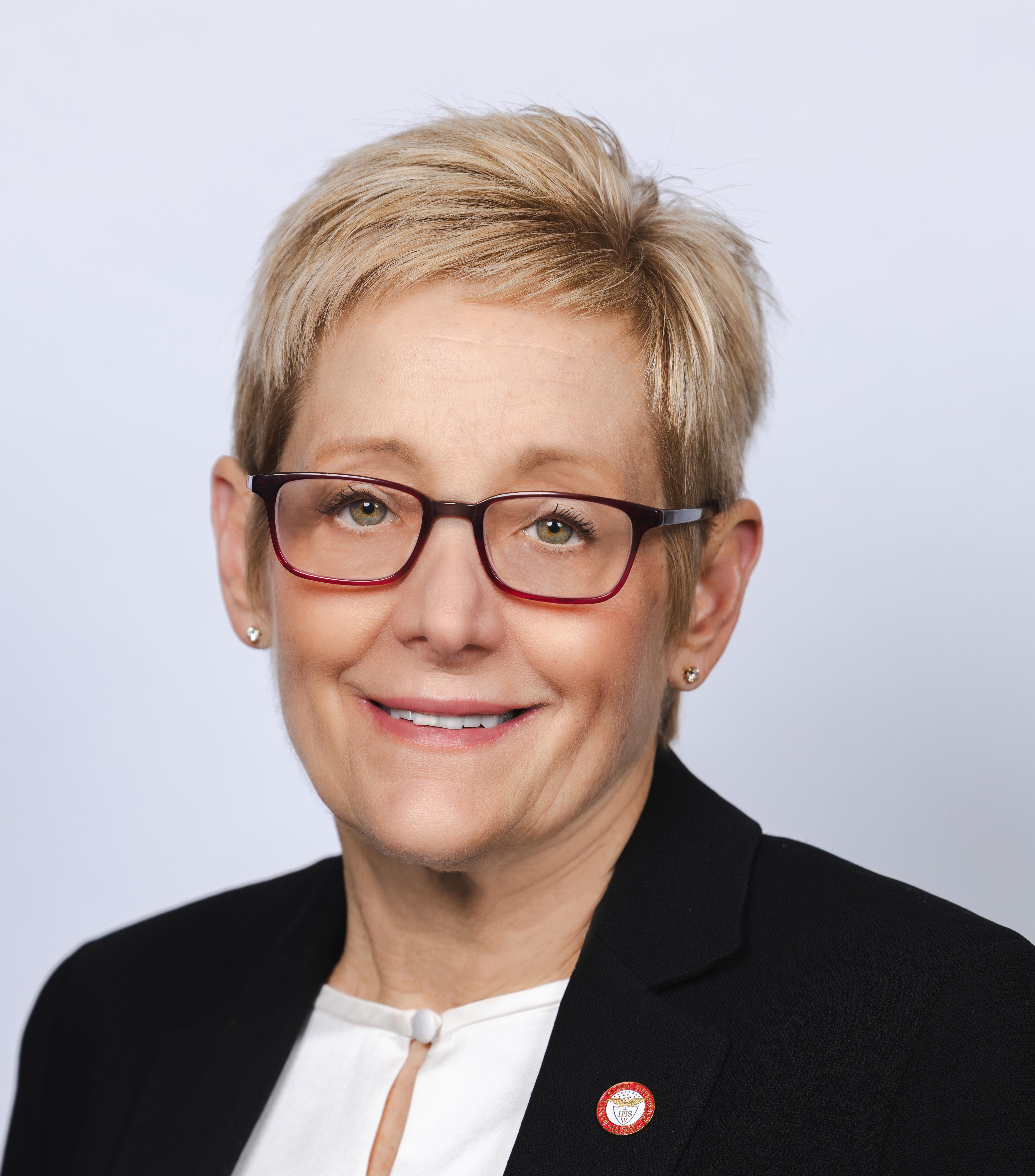 Head Shot of smiling woman with short blond hair and red glasses