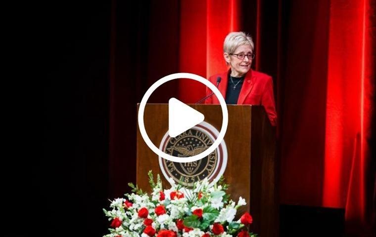 President Julie Sullivan speaking at a podium with a bouquet of roses in the foreground