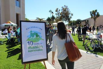 Person walking near a sign that reads Sustainability Day.