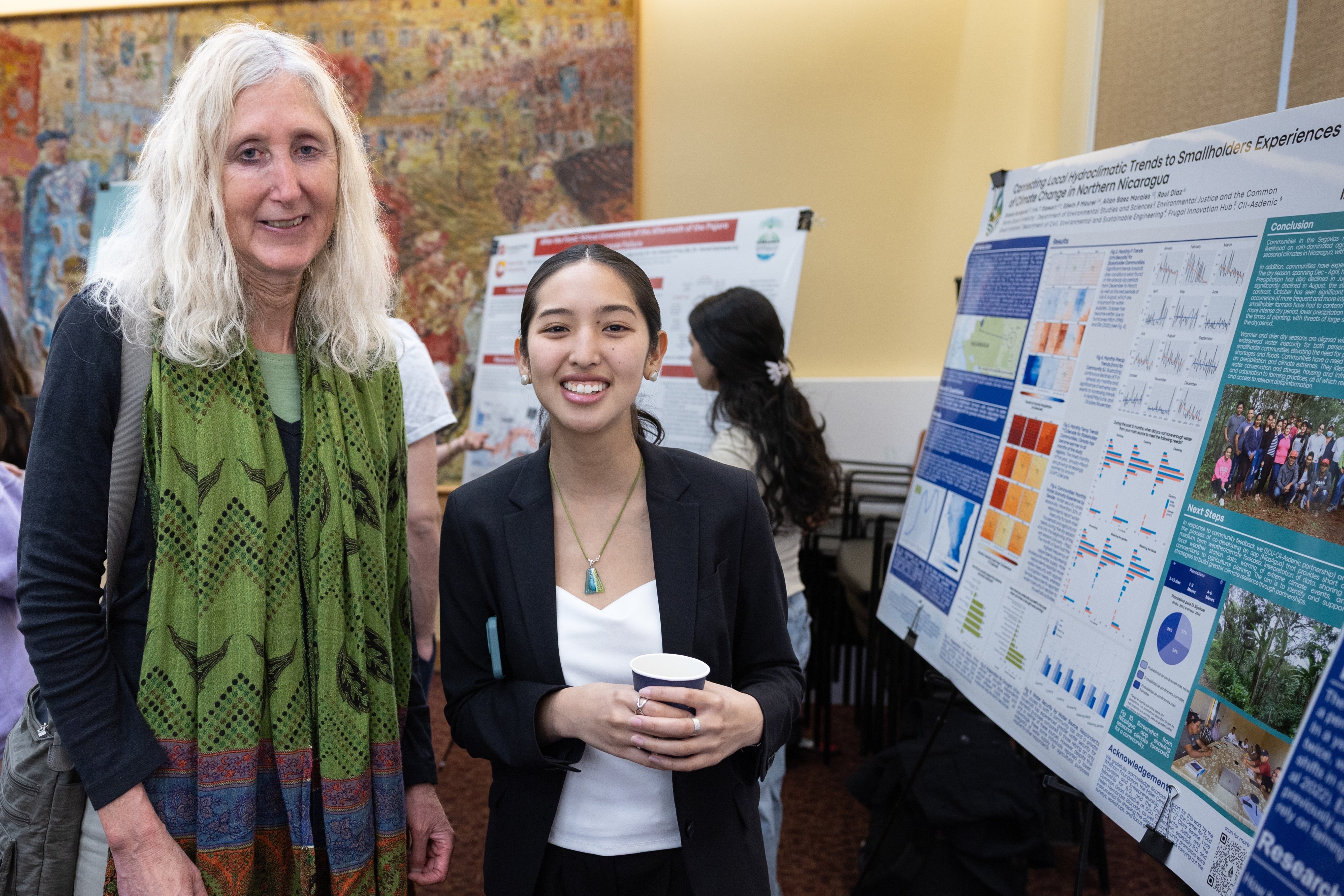 A faculty member and student stand in front of the latter's research poster on hydroclimatic trends during the 2025 Sustainability and EJ Symposium.