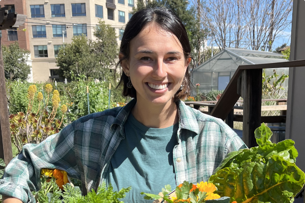 Profile photo of Becca Nelson in a garden holding baskets of produce