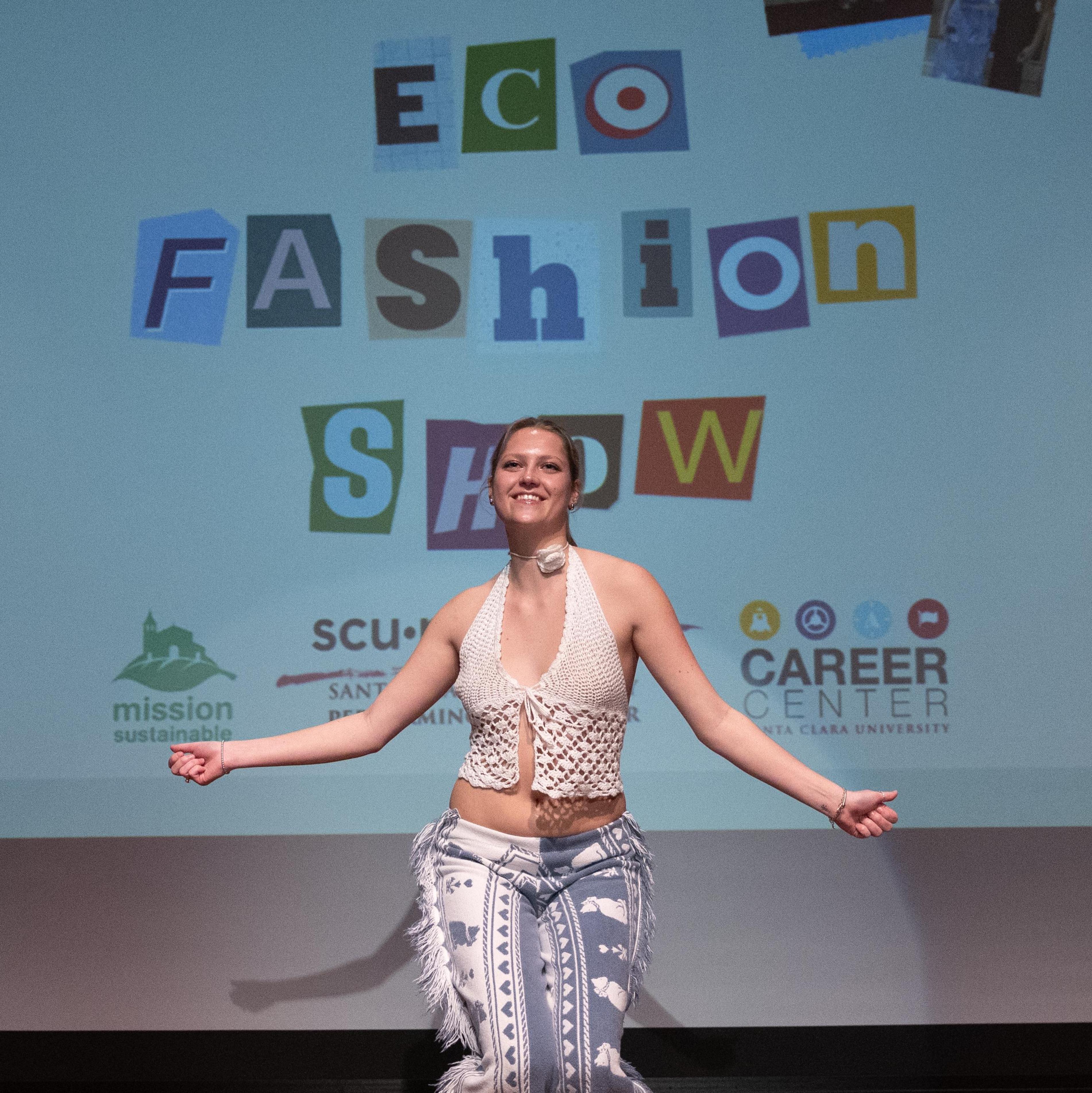Female model with arms outstretched in front a screen that says EcoFashion Show