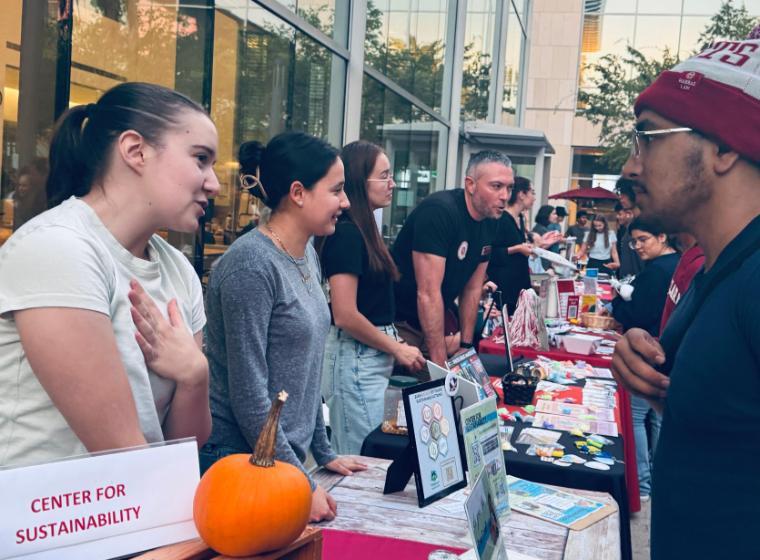 2 sustainability coordinators talking to students at a tabling event 
