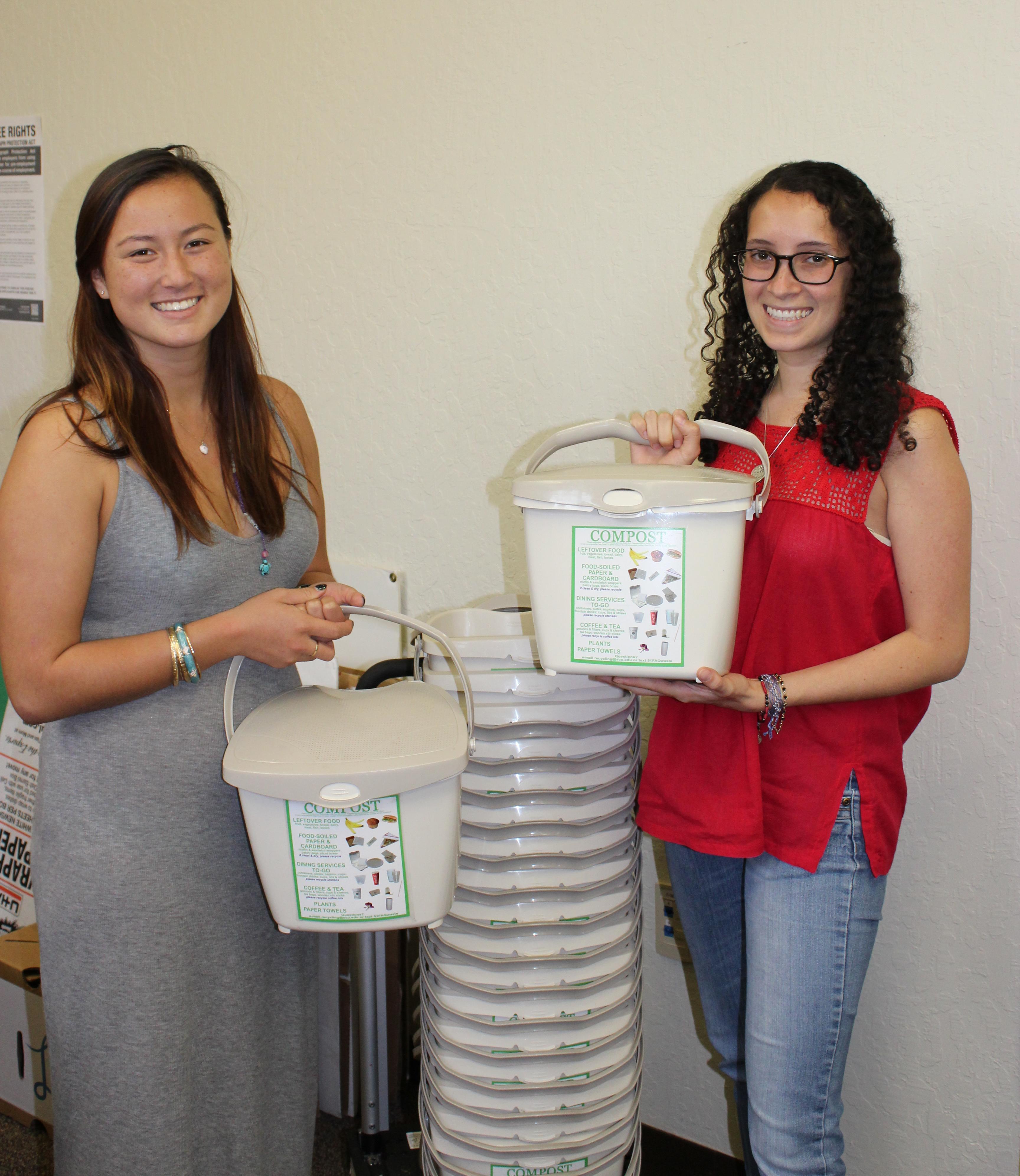 Two women holding compost bins in a room titled Villas Composting.