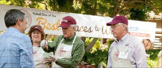 Four people talking outside near a sign with BEST PLACES TO WORK text.