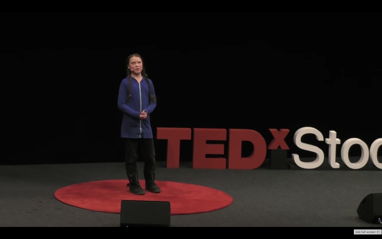 Climate activist Greta Thunberg speaks on stage with the words TEDx Stockholm written behind her