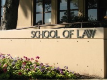 Building sign reading 'School of Law' with flowers in front.