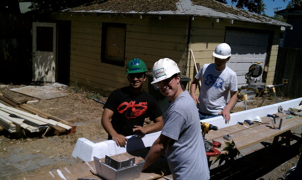 People building with bricks outside a house.