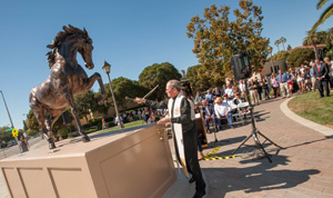 People gather around a statue of a rearing horse outdoors.
