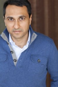 A person wearing a blue sweater and a white shirt. image link to story