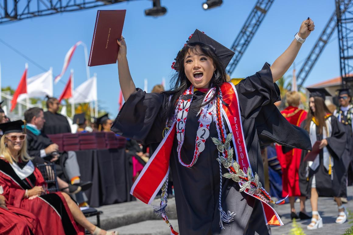 Student in cap and gown holding diploma image link to story
