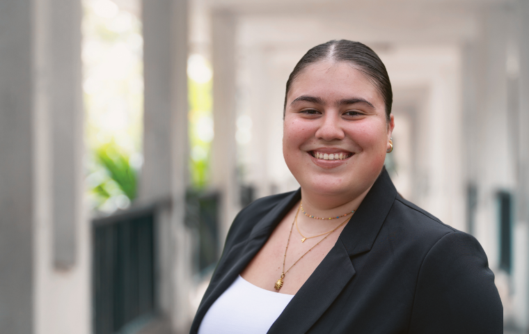 A young woman in a white blouse and black jacket standing in a hallway