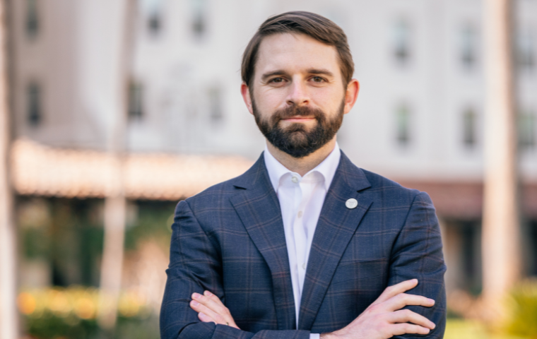 Frank Tessier standing with him arms folded near the mission wall