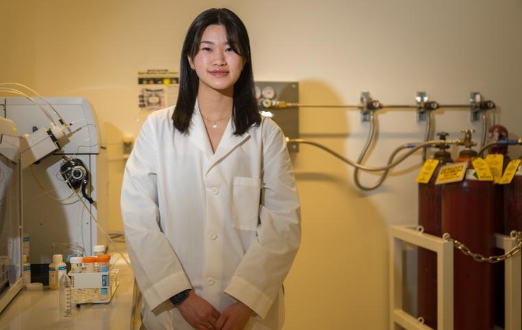 Samantha Lei, a young asian woman wearing a white lab coat looks to the camera.
