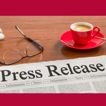 Glasses sit on a table next to a coffee mug and a newspaper that reads Press Release