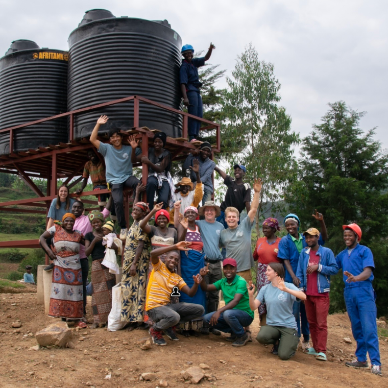 Group of people celebrating near water tanks in Rwanda for EWB 2022 project. image link to story