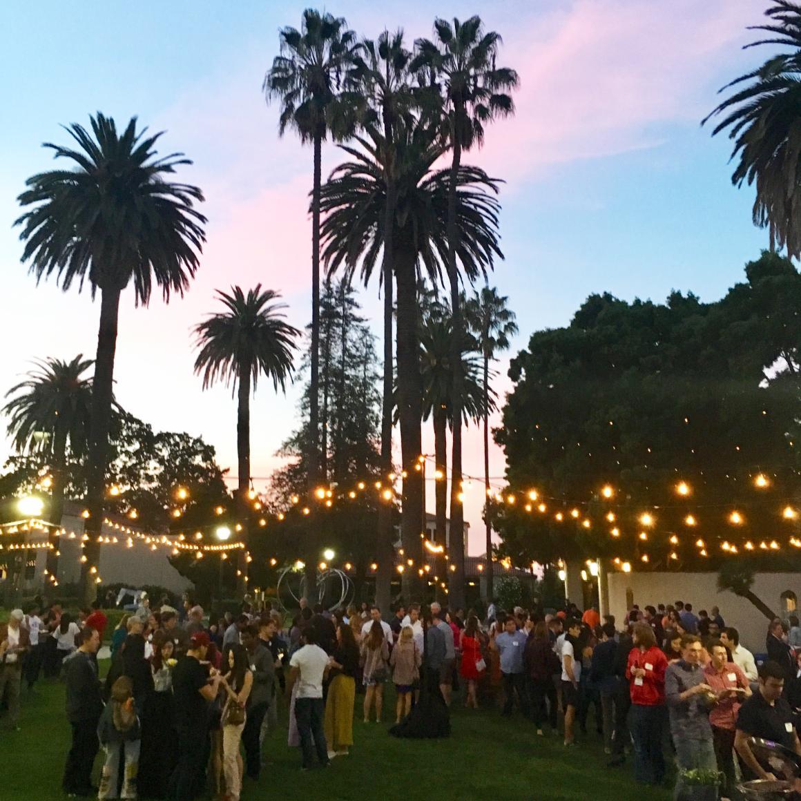 Alumni, faculty, and friends enjoy the Big Bash Block Party under festive lights and surrounded by palm trees.