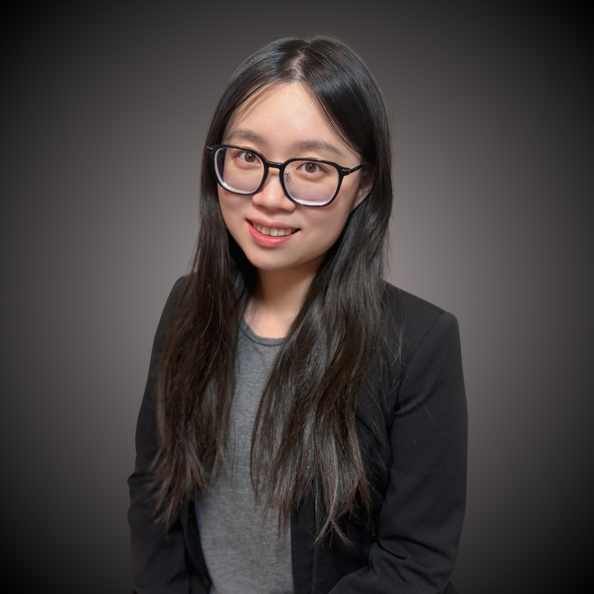 A woman with black frames wearing a gray top and black blazer
