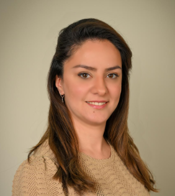 A woman smiling at the camera against a neutral background.