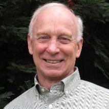 An older person smiling in an outdoor setting.