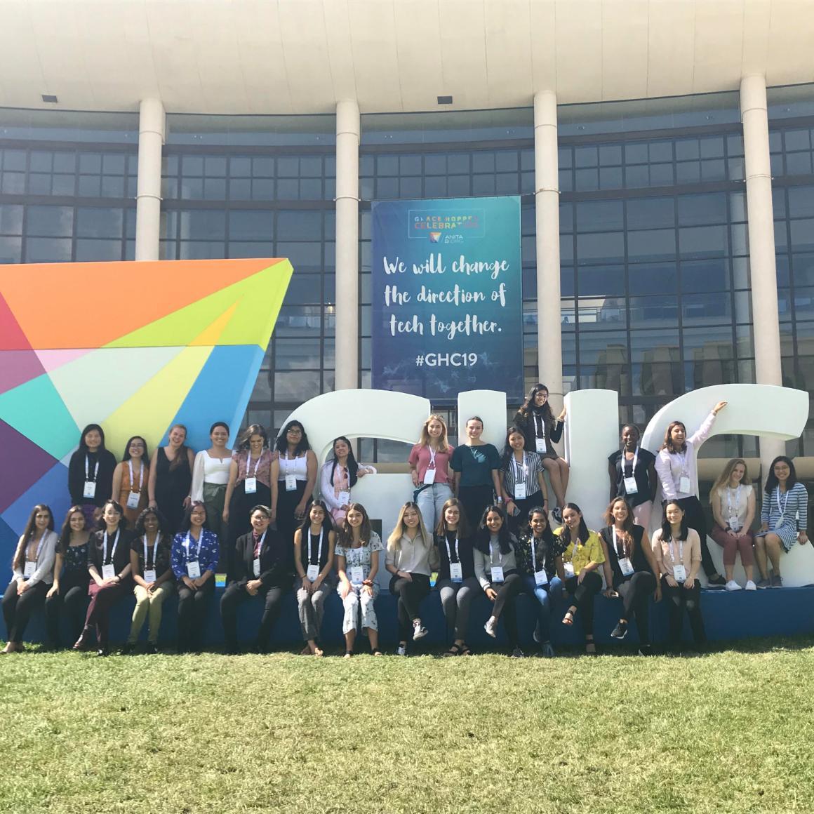 SCU students at Grace Hopper Conference 2019 in front of banner reading We will change the direction of tech together