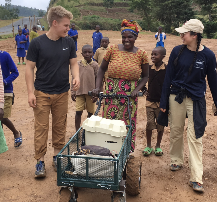 A group of people walking with a cart of supplies.