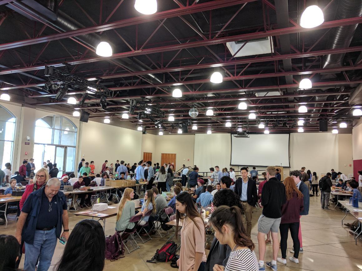 People attending a robot show in a large indoor space.
