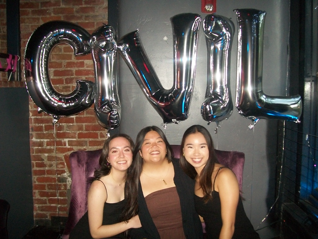 Three girls posing in front of balloons spelling out CIVIL