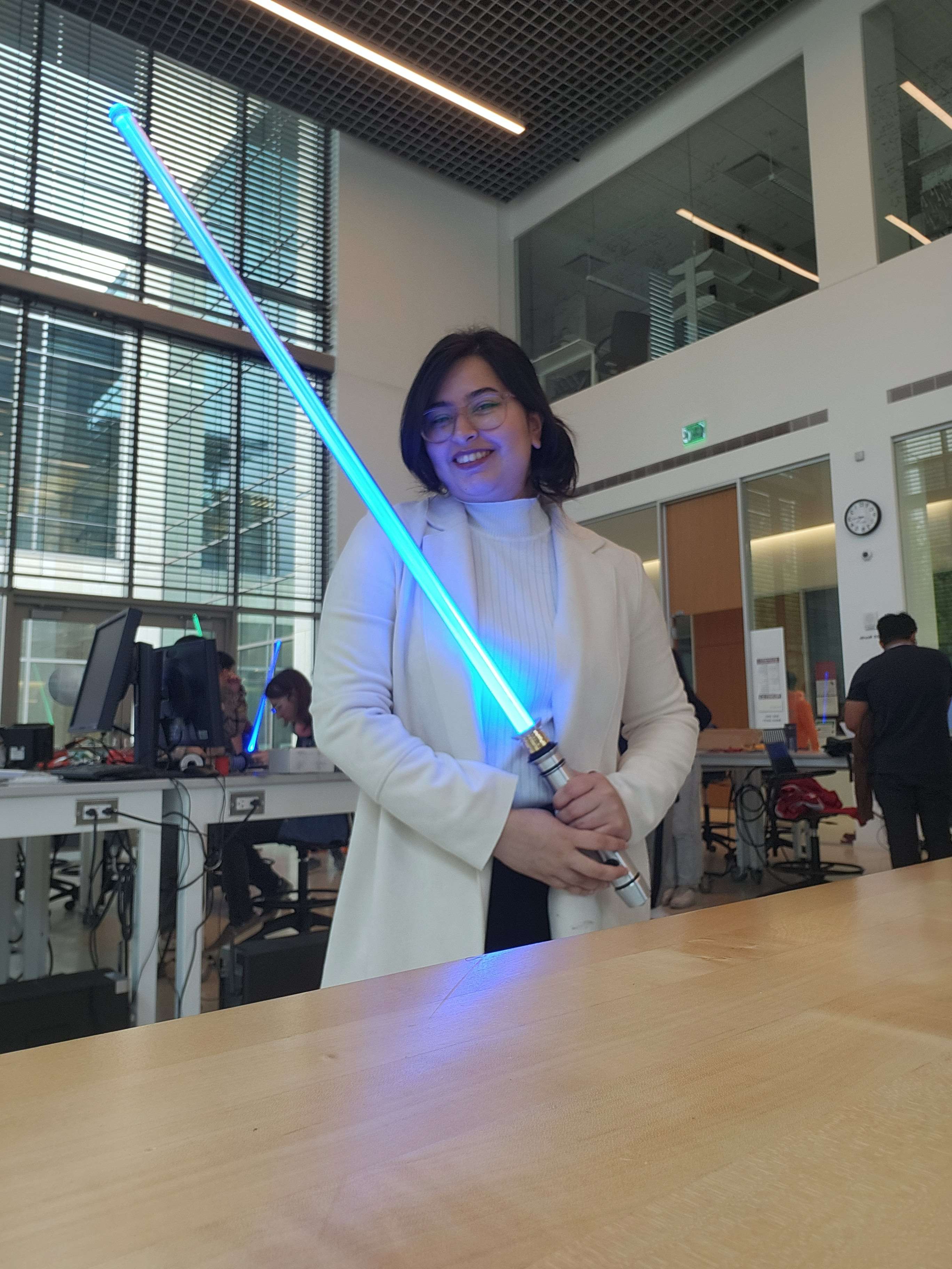 A member of the Maker Club holding up a blue lightsaber they created.