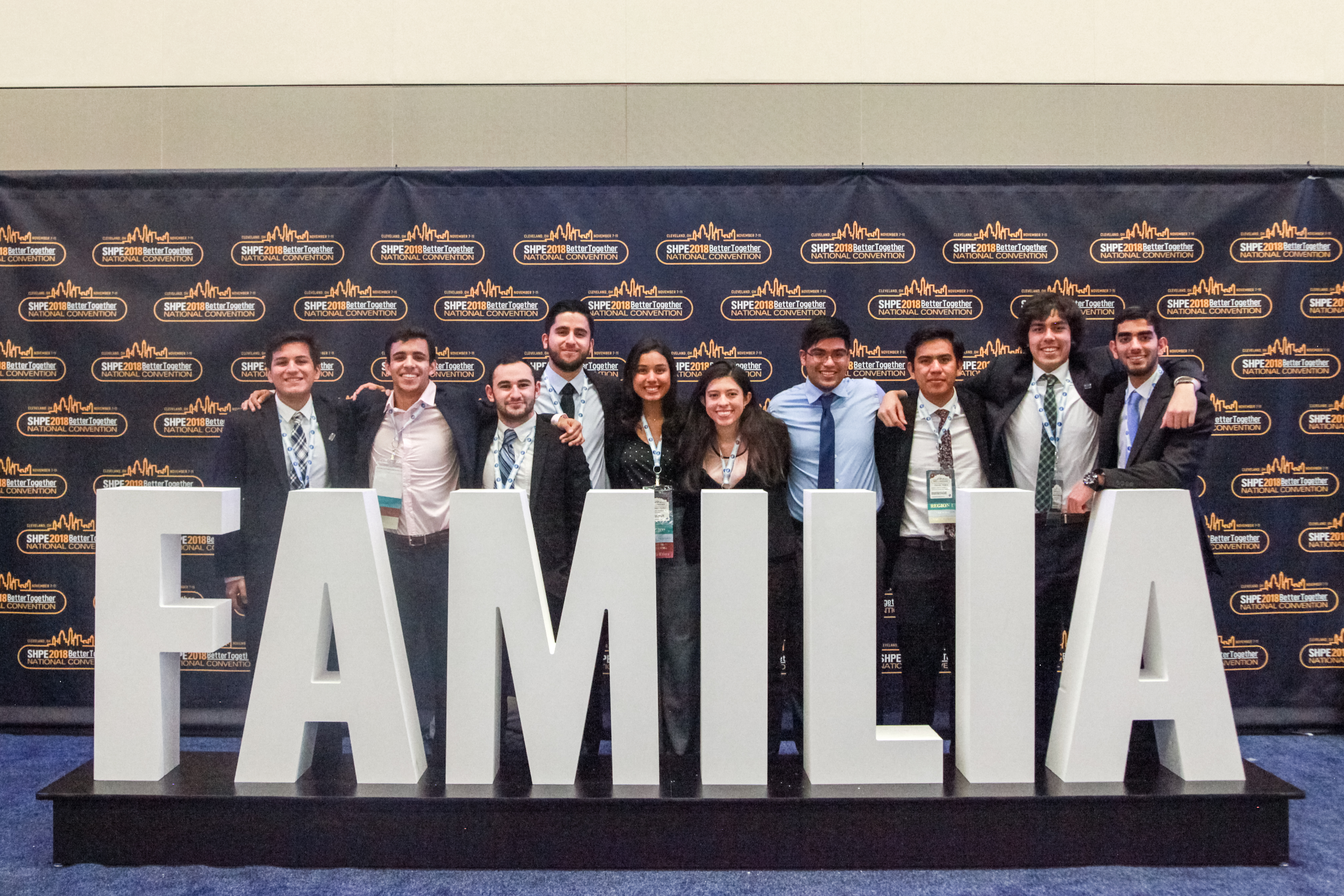 Group of people posing behind large letters spelling FAMILIA at the SHPE Conference.