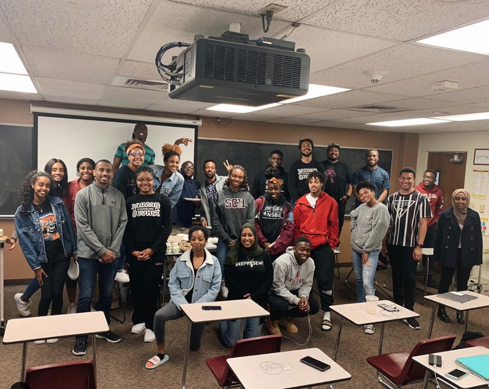 A group of students and alumni in a classroom.