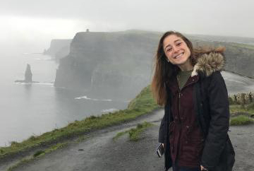 Person smiling with Cliffs of Moher, Ireland, in the background. image link to article