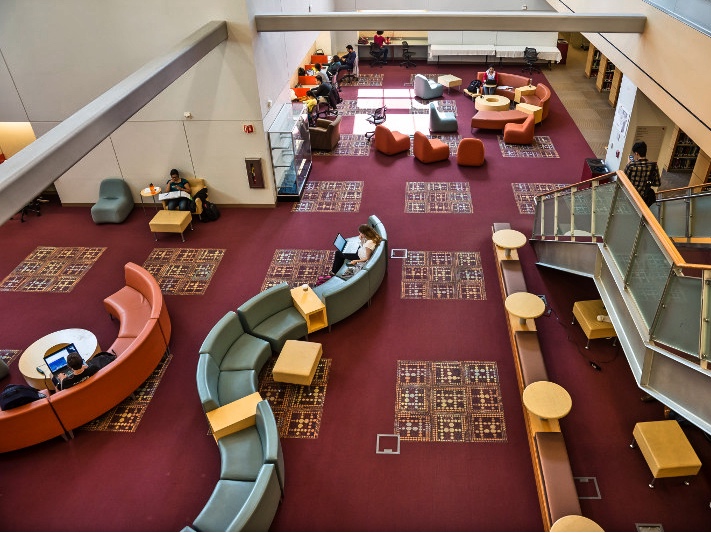 Looking down onto the colorful lower level of Learning Commons with seating and tables.