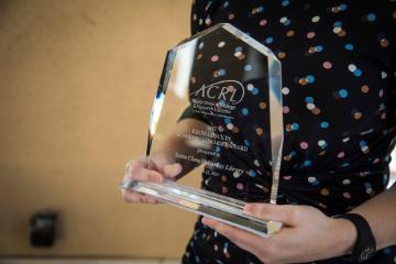 A person holding an ACRL award trophy.